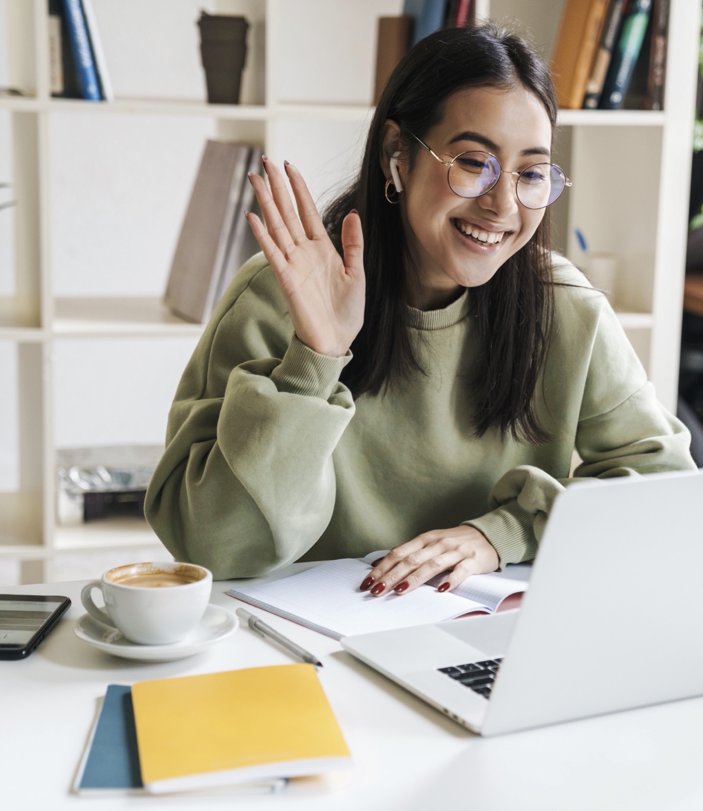 Girl smiling and waving at laptop